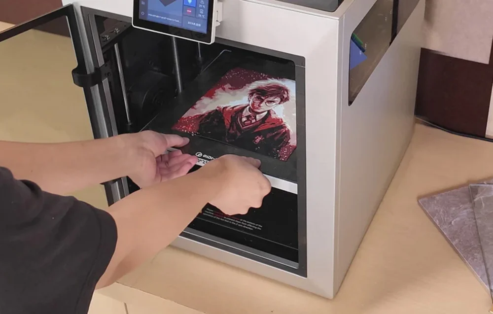 Użytkownik wyciągający gotowy model 3D z komory drukarki zaraz po zakończeniu automatycznego procesu.